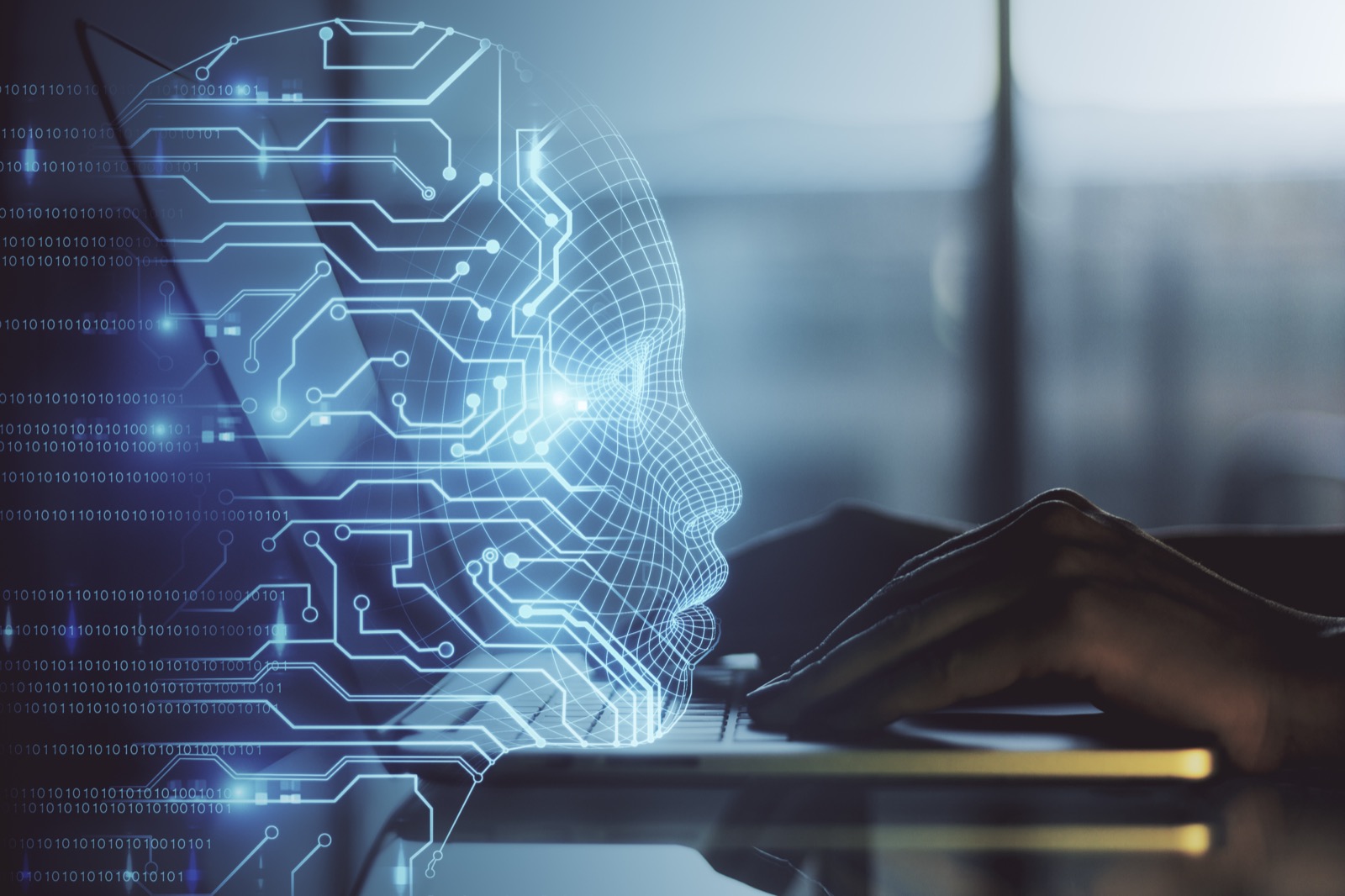 A wireframe head formed from circuit-board traces beside hands typing at a laptop — applied AI