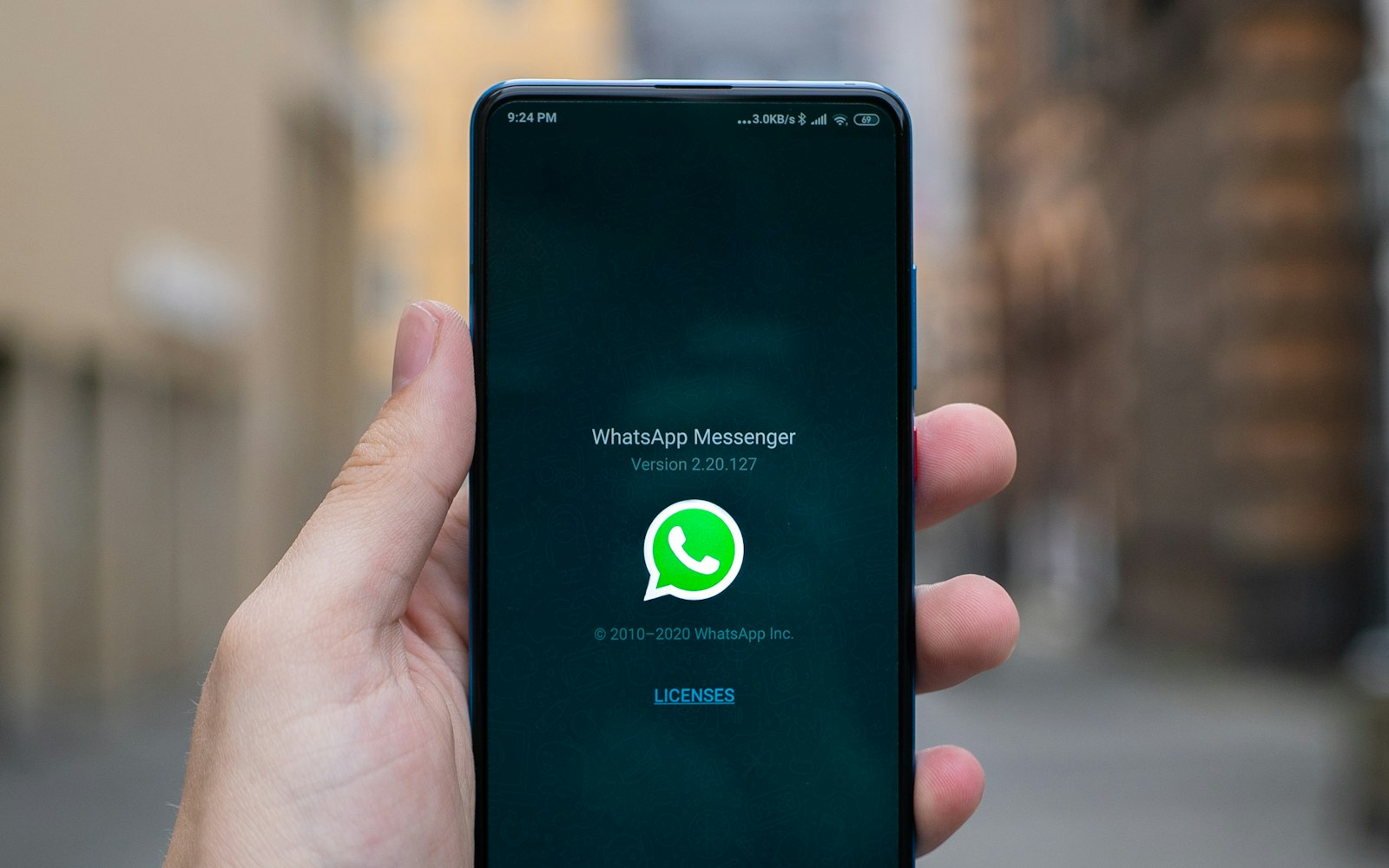A hand holding a phone showing WhatsApp Messenger